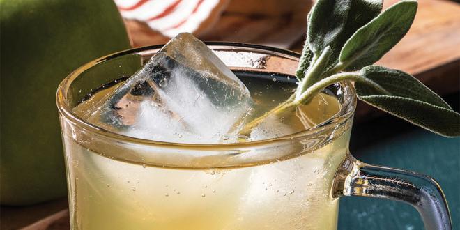 a glass of bubbly cider garnished with sage