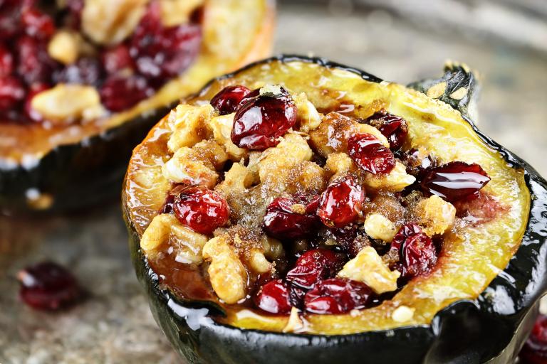 An acorn squash half stuffed with meat, dried cranberries, and walnuts.